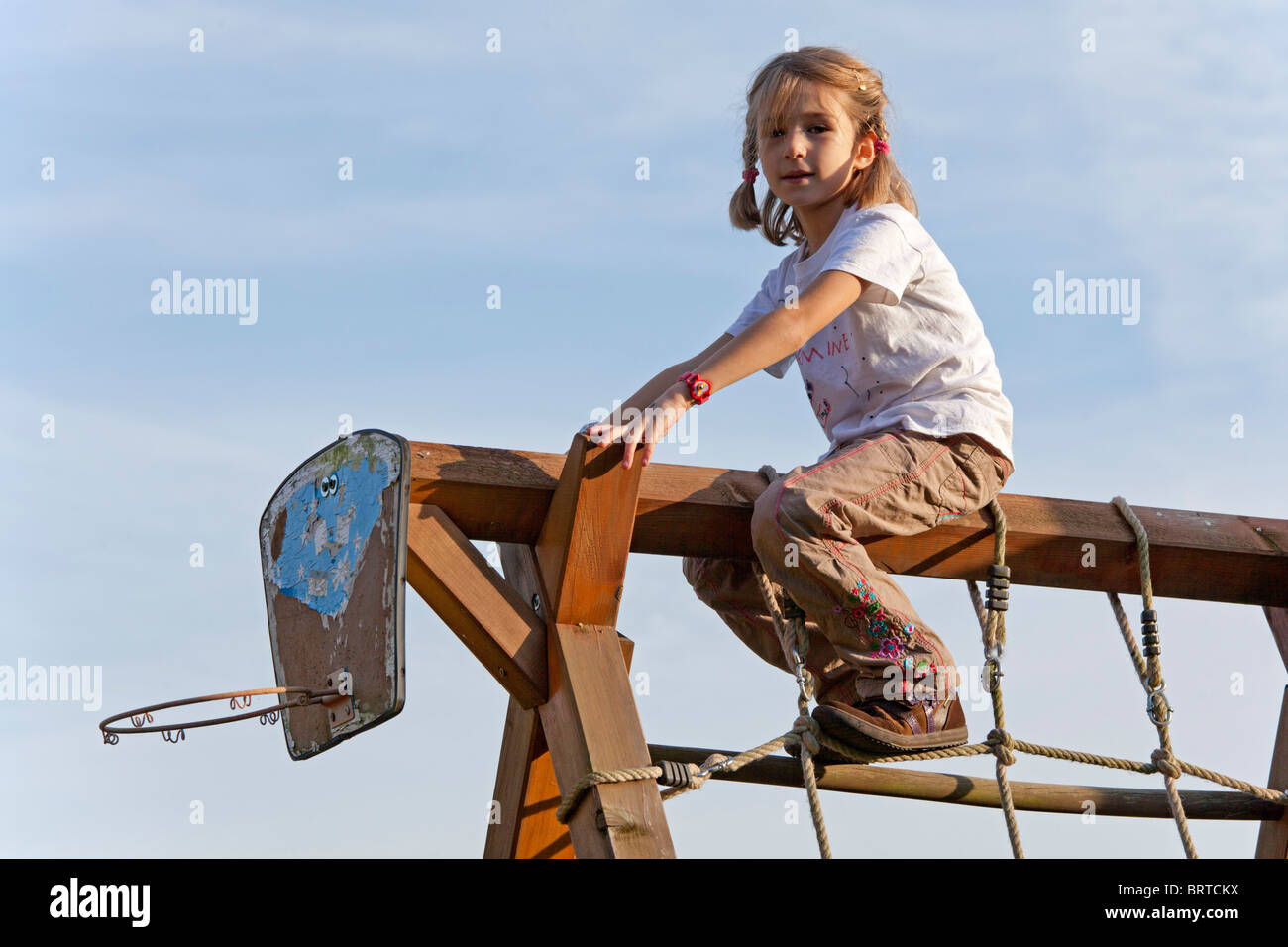 little girl sitting on monkey bars Stock Photo