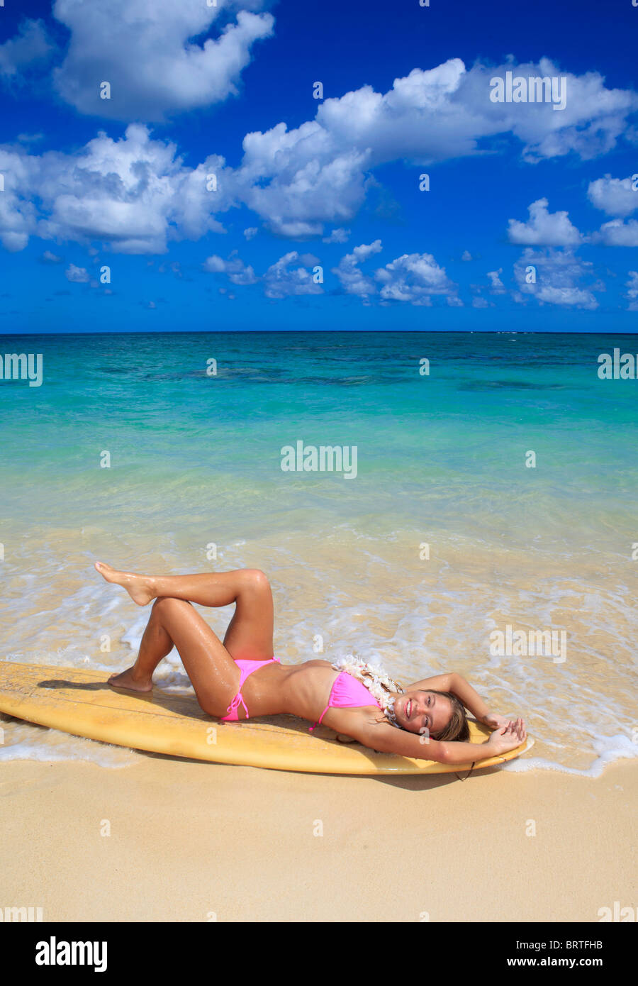 teenage girl in pink bikini at the beach in hawaii lounging on her