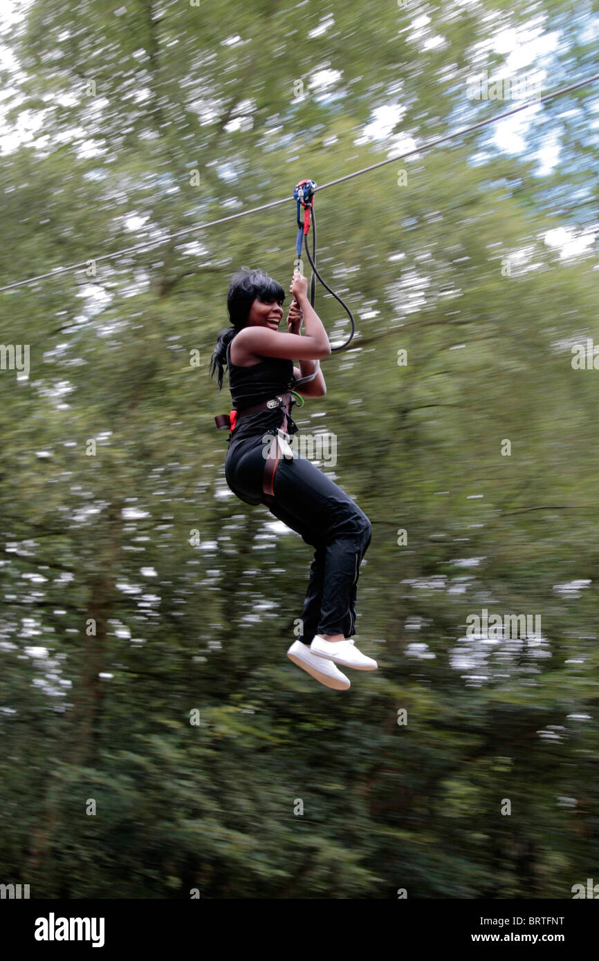 A woman flying down a zip line at a Go Ape centre at Black Park Country Park, Wexham, UK Stock