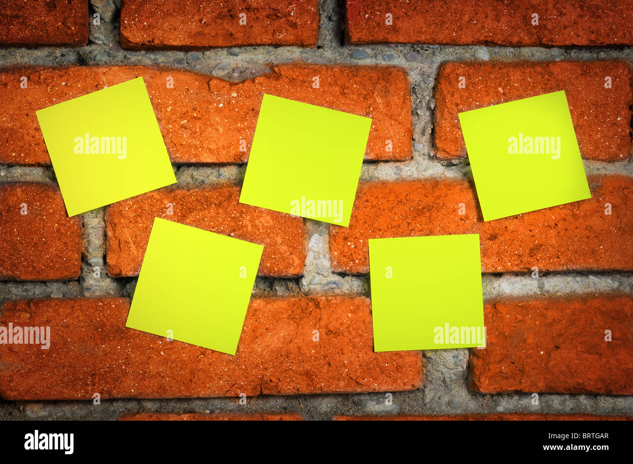 Yellow sticky notes on an old shabby red brick wall. Stock Photo