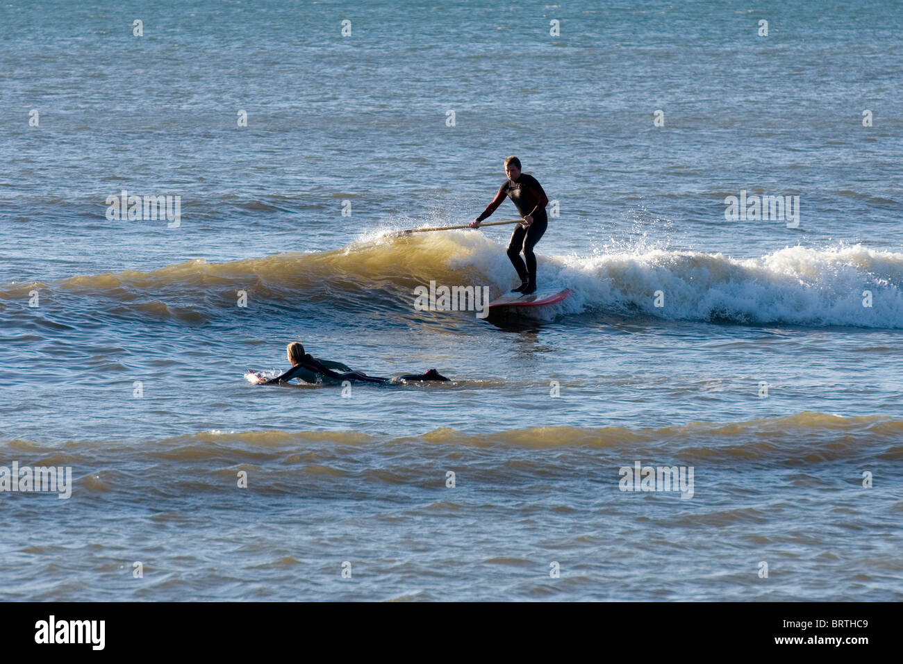 A surfer with a paddle carving in Aberystwyth's main surf spot the Trap