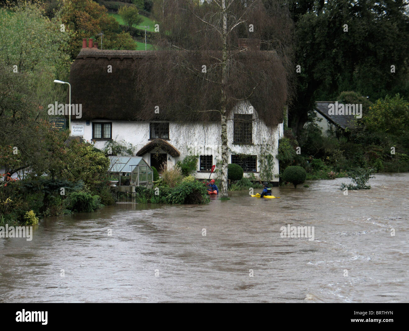 canoeists in flooded garden of Bickleigh Cottage near bridge thatched river exe Devon UK Stock Photo
