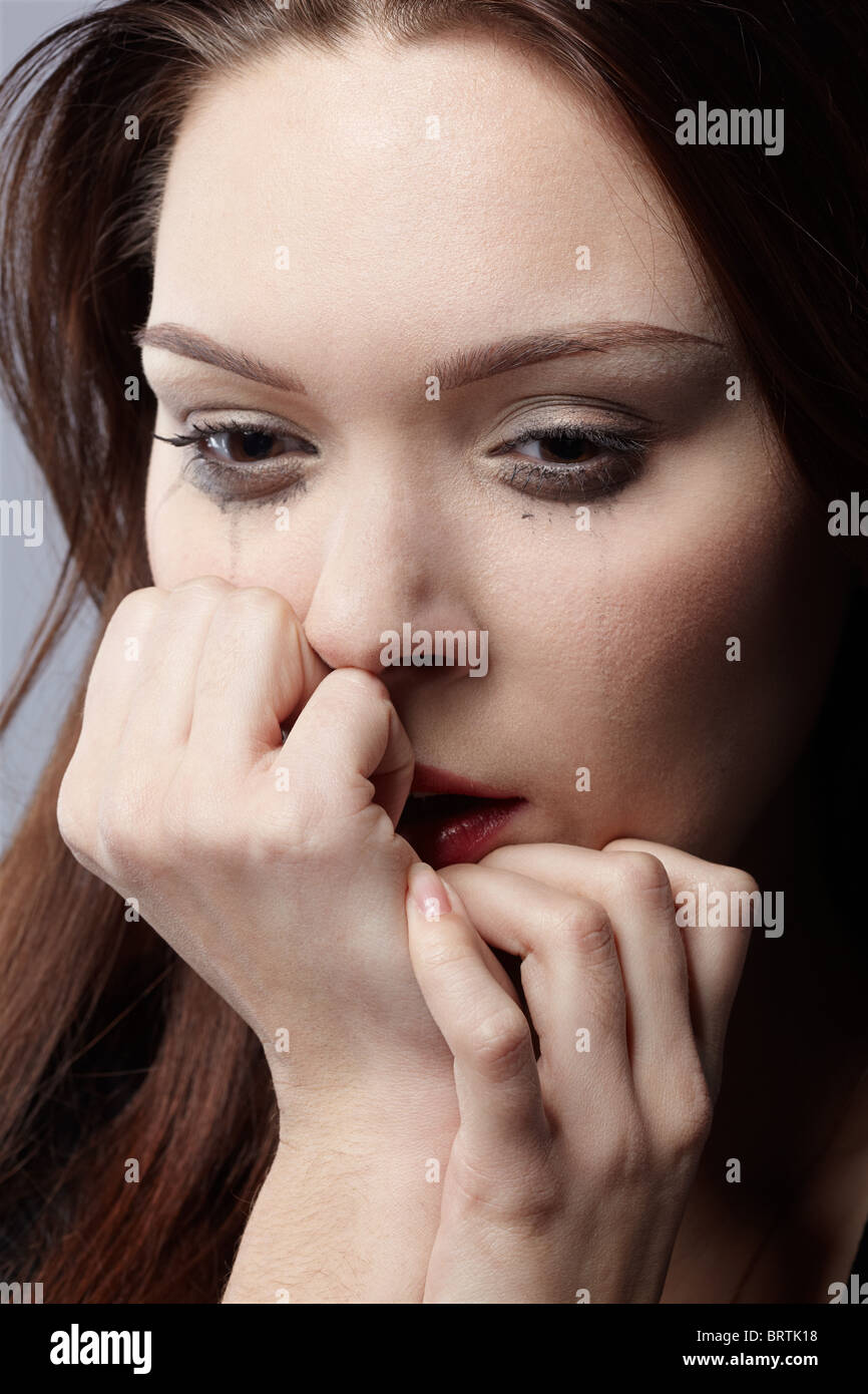 portrait of beautiful crying girl with smeared mascara hiding her face
