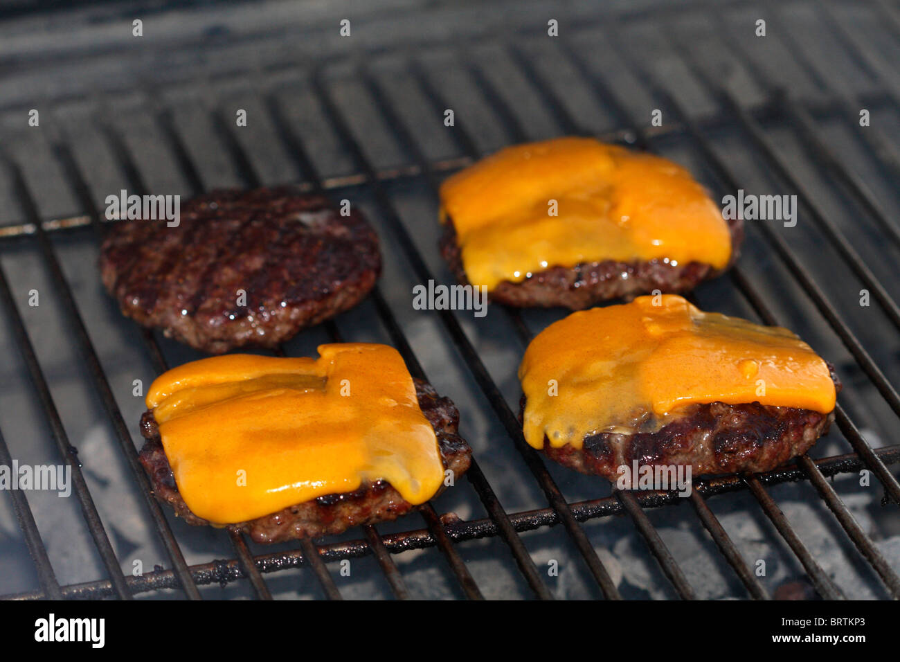 Hamburger patties with cheese cooking on a grill Stock Photo Alamy