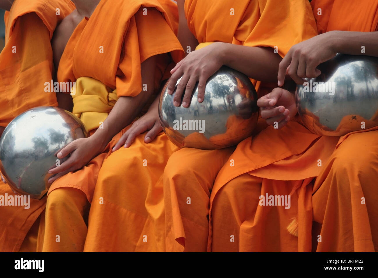 Buddhist monks wearing orange robes sit with their alms bowls near Tha Pae Gate in Chiang Mai