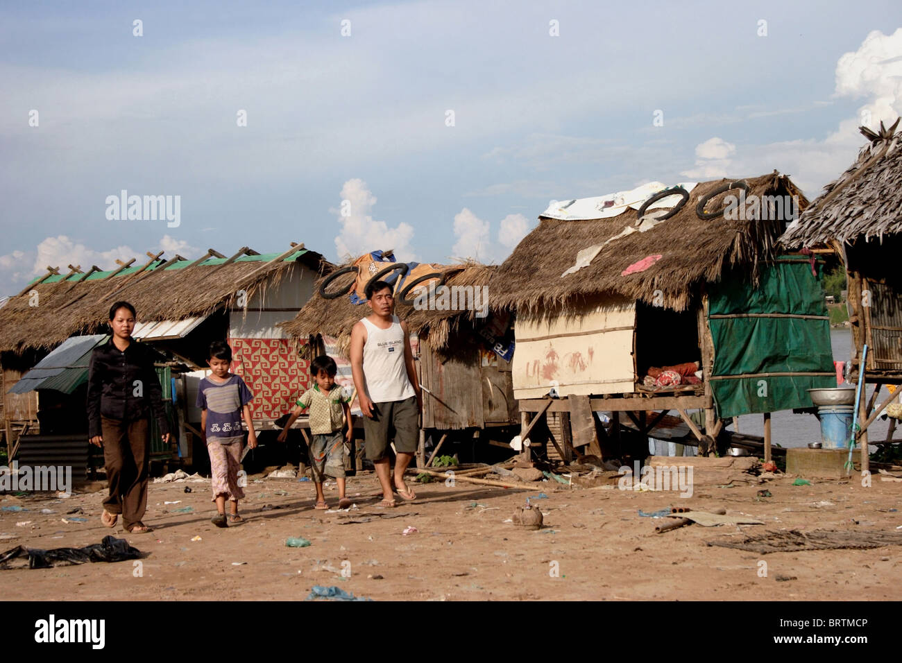 A family is leaving a squatter's slum where people are living in poverty on the bank of a Mekong River in Kampong Cham Cambodia. Stock Photo