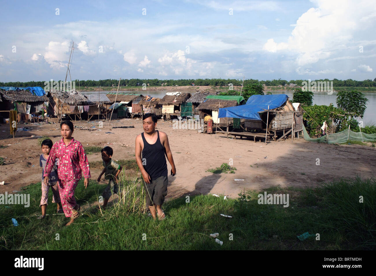 A family is leaving a squatter's slum where people are living in poverty on the bank of a Mekong River in Kampong Cham Cambodia. Stock Photo