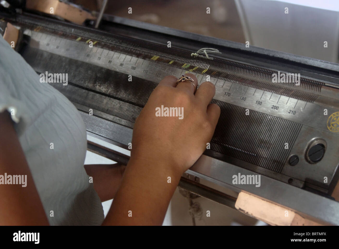 A young Khmer woman is using her hands with precision while working at her machine in a garment factory in Cambodia Stock Photo