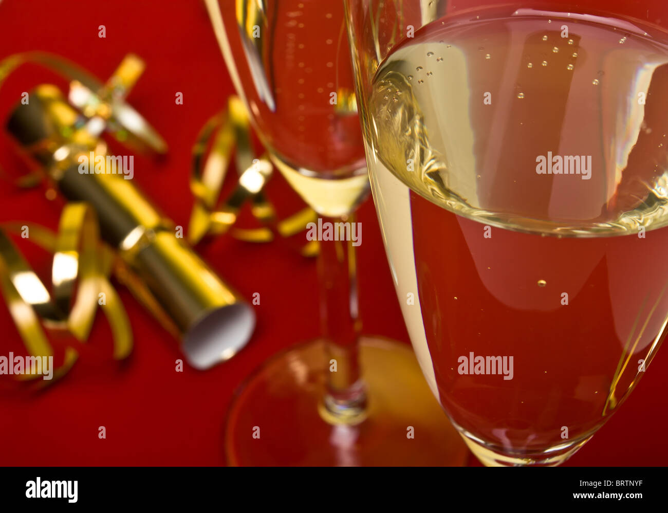 Festive celebration concept of champagne, ribbons and crackers under a golden light. Stock Photo