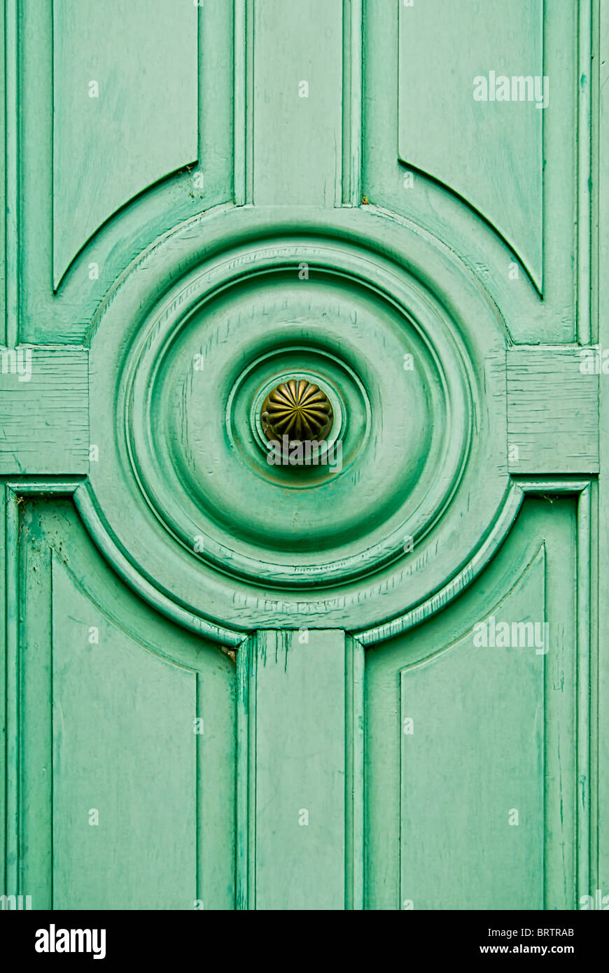 A wooden door, painted in green, with a brass door knob. Stock Photo