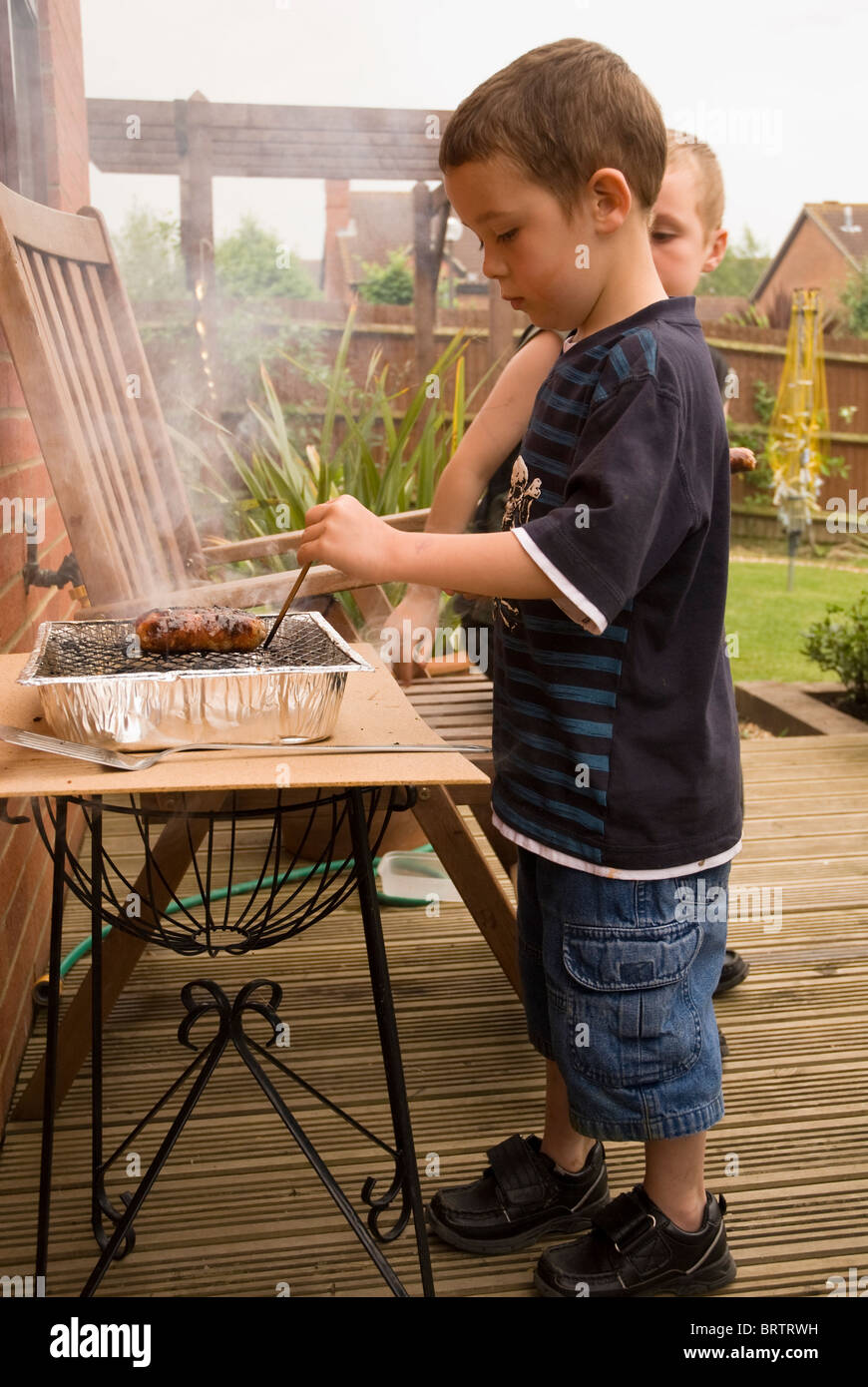 A child cooking on a disposable barbecue Stock Photo