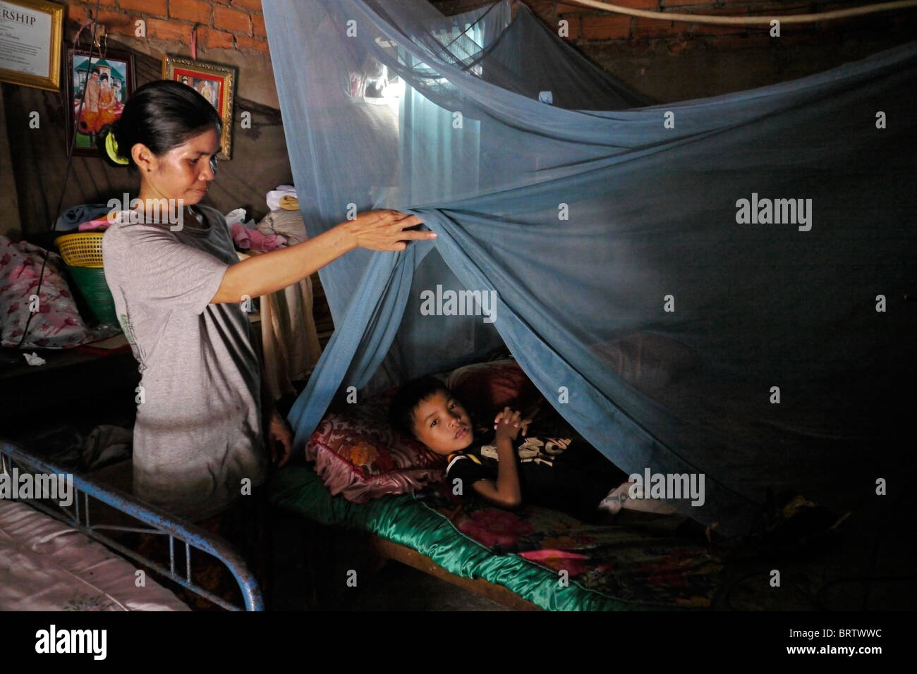 CAMBODIA 8-year-old Khoeun Sovan in bed under mosquito net, Mean Caeay slum, Phnom Penh. PHOTO by SEAN SPRAGUE Stock Photo