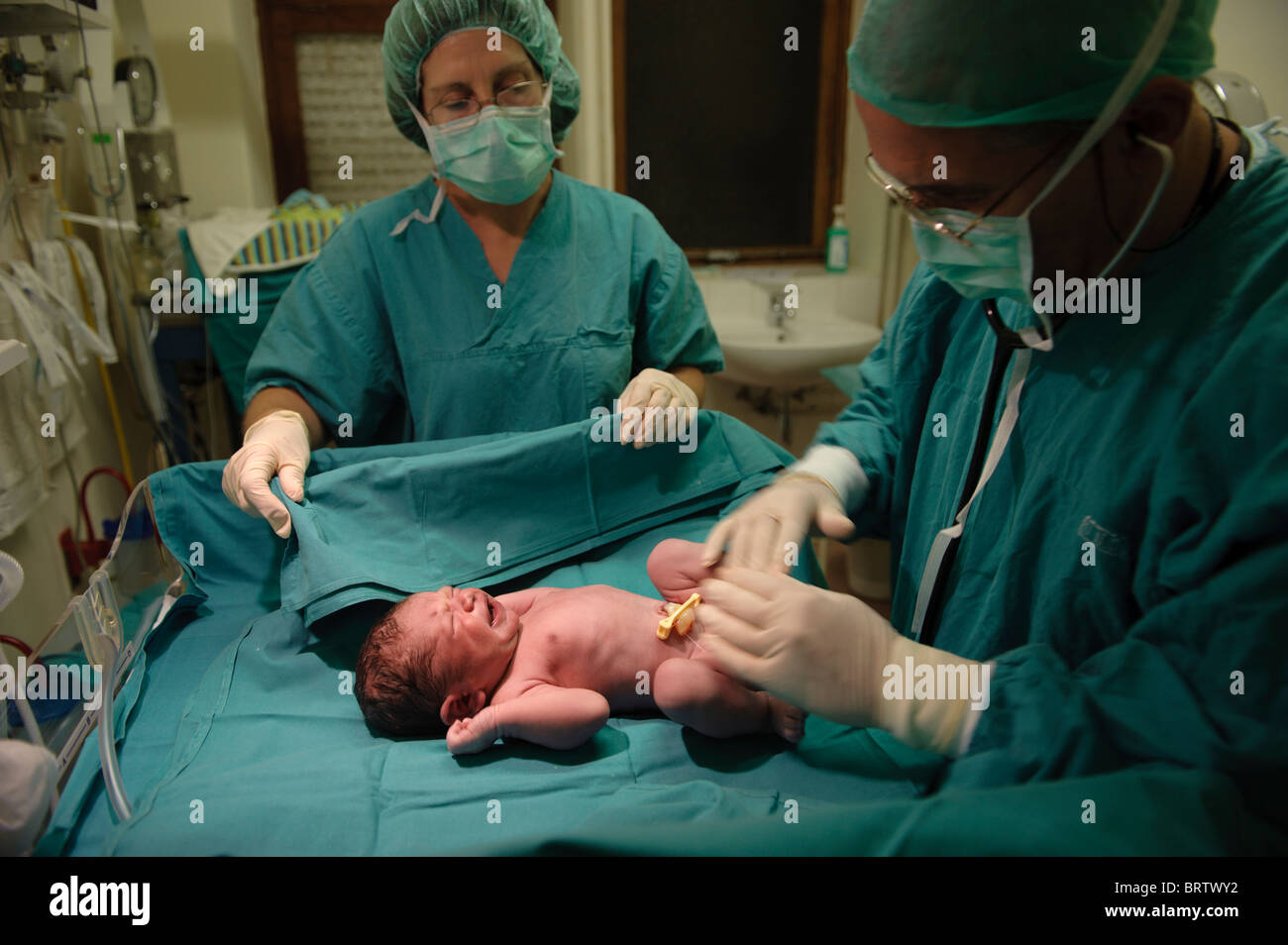 Newborn baby is examined by a nurse and a doctor after a caesarian birth Stock Photo