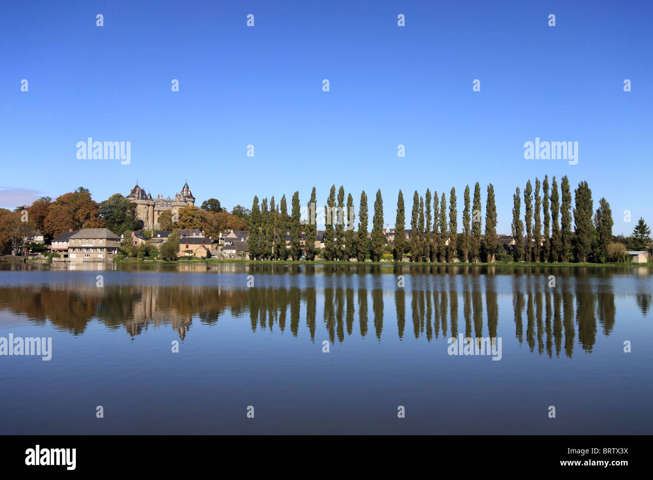 The Château de Combourg and a row of trees, reflected in the waters of Lac Tranquille, in Brittany, northern France Stock Photo