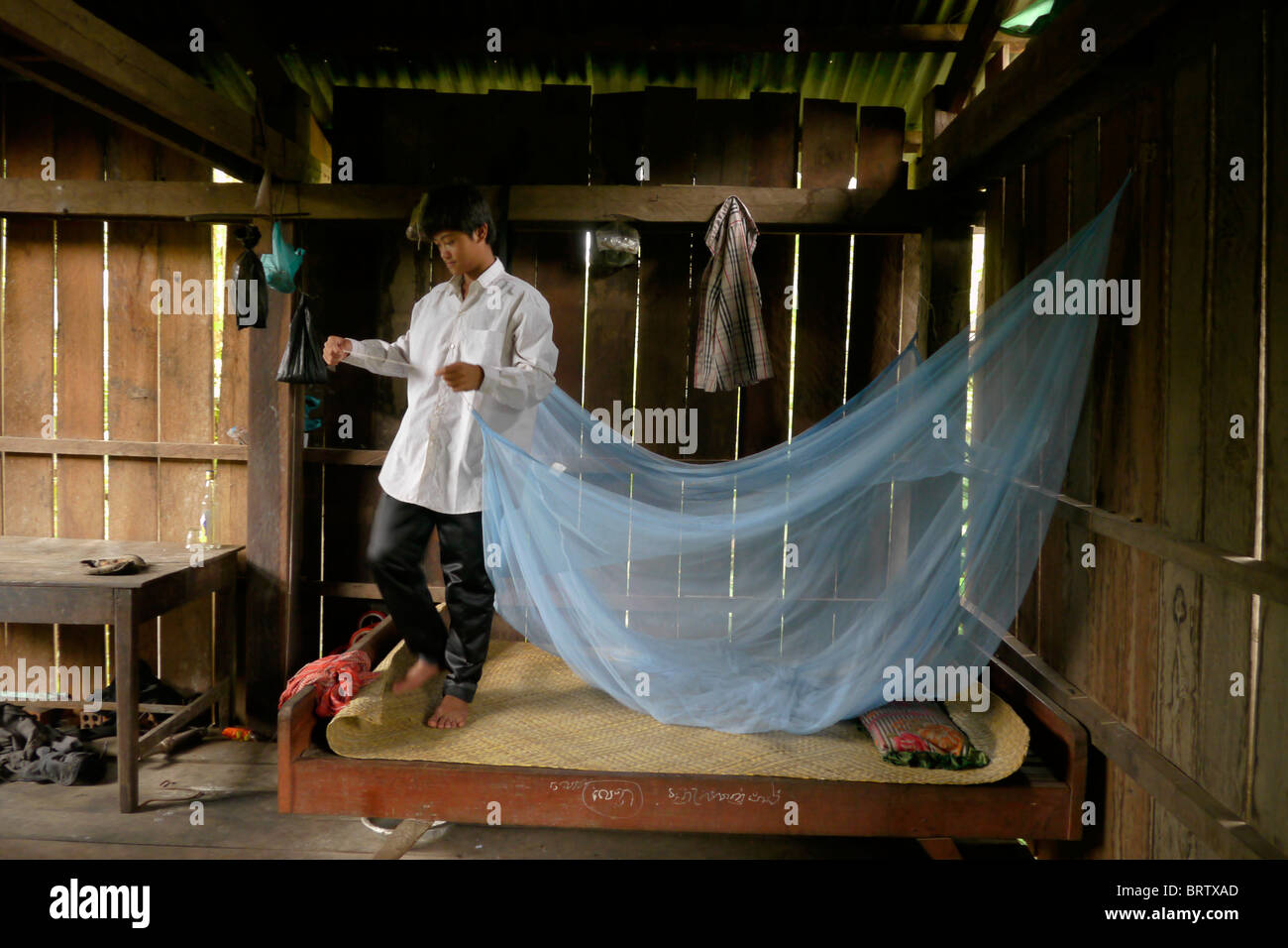 CAMBODIA Phala Lekha (15) arranging the mosquito net over his bed, Kamphun village, Stung Treng district. PHOTO by SEAN SPRAGUE Stock Photo