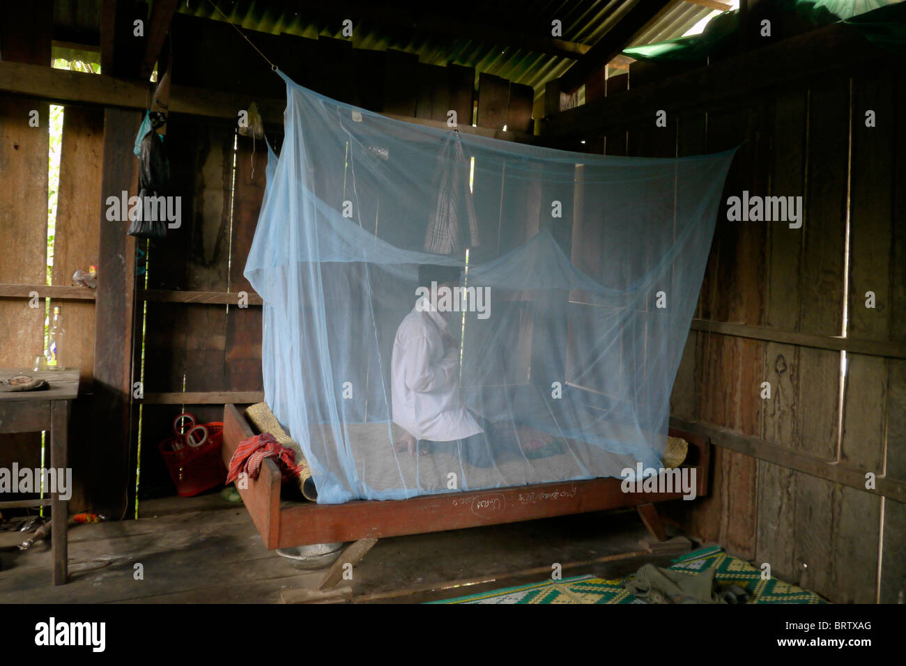 CAMBODIA Phala Lekha (15) arranging the mosquito net over his bed, Kamphun village, Stung Treng district. PHOTO by SEAN SPRAGUE Stock Photo