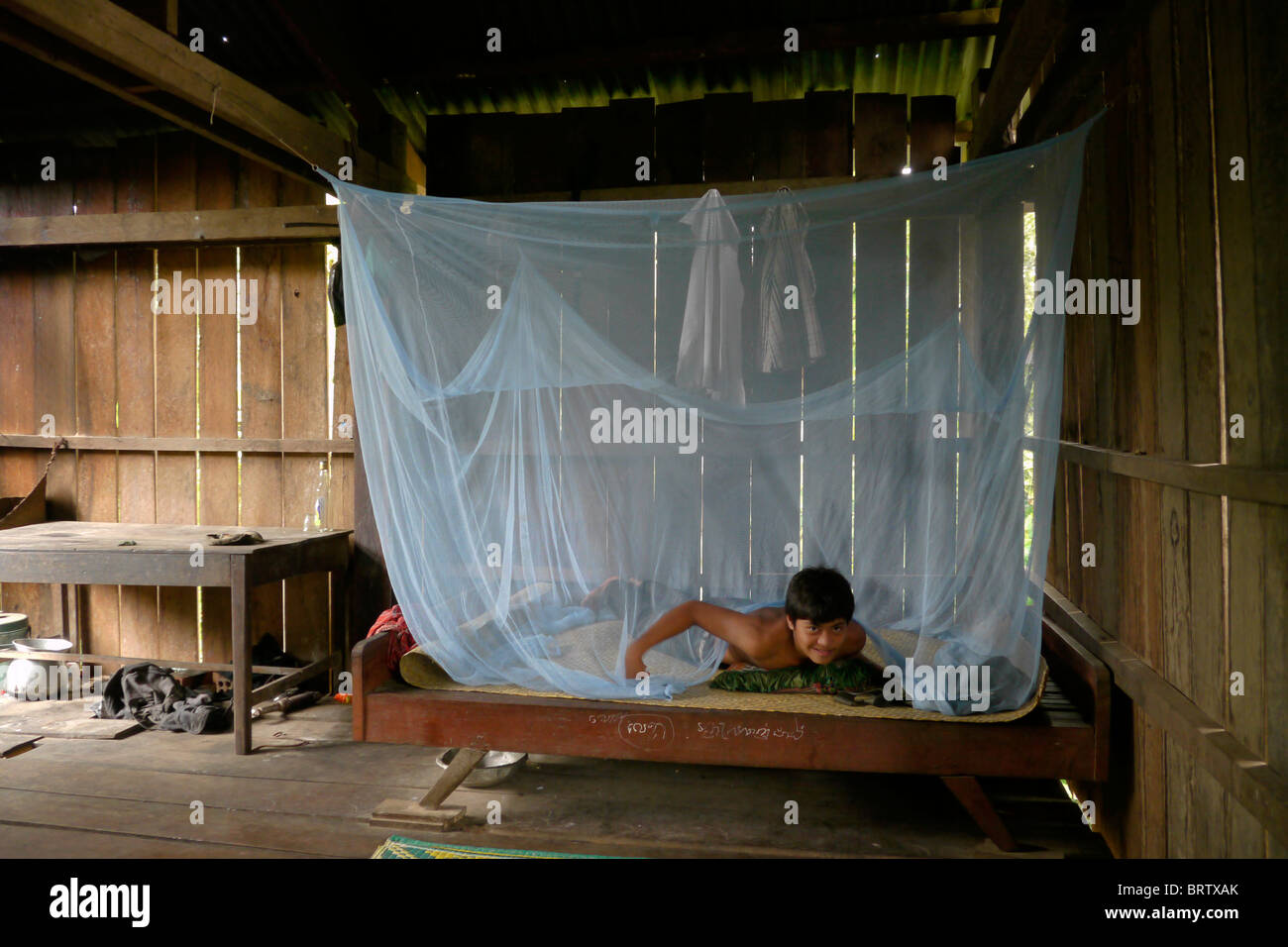 CAMBODIA Phala Lekha (15) arranging the mosquito net over his bed, Kamphun village, Stung Treng