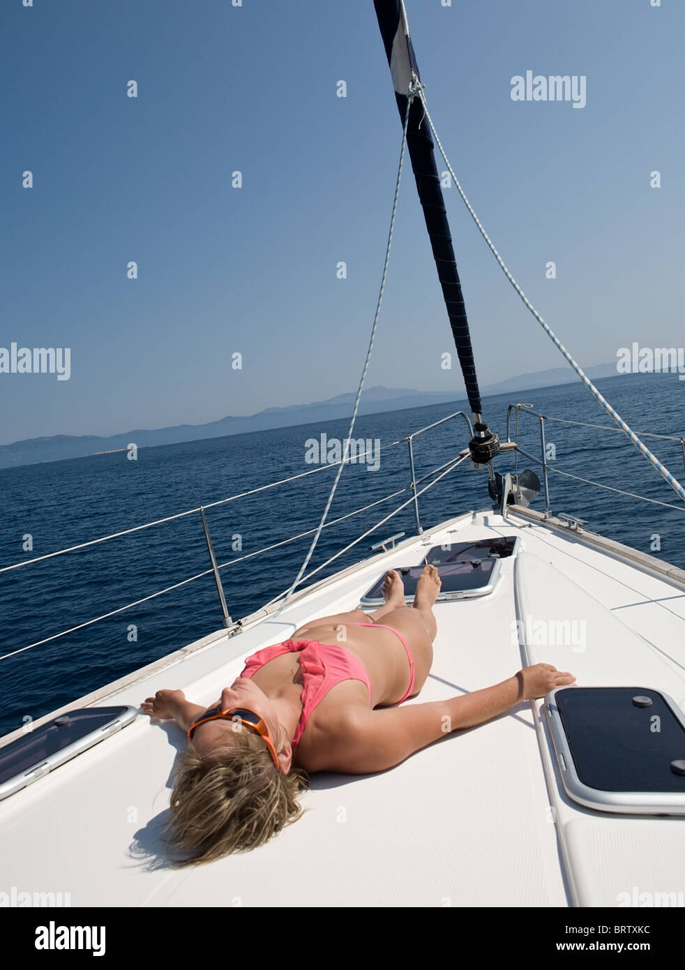 woman in pink swimsuit lying sunbathing on deck of yacht Stock Photo