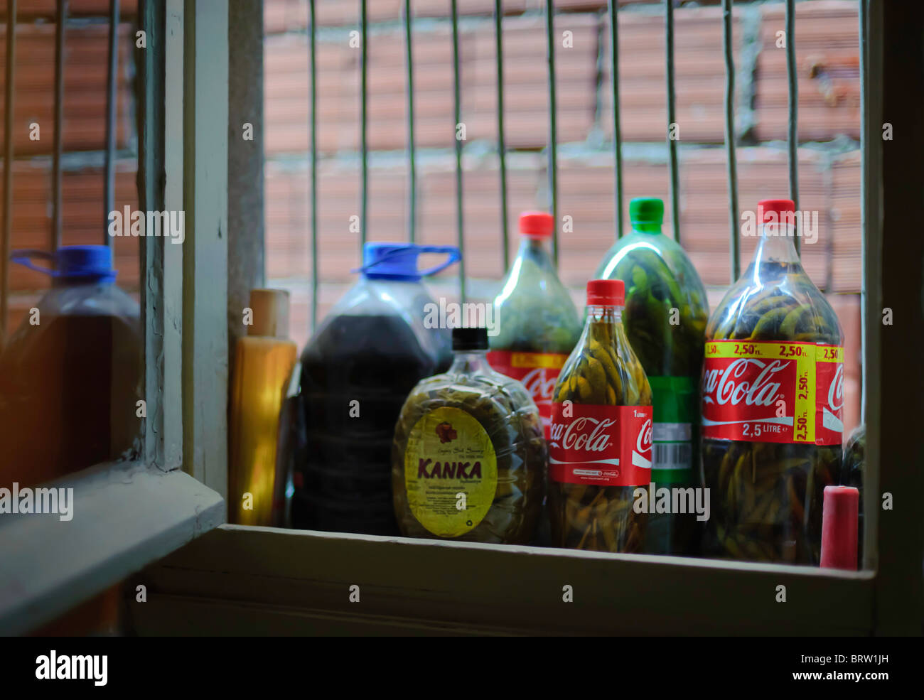 Pickled peppers held in reused soft drink bottles as shown on the window sill of an inner city apartment house in Izmir, Turkey. Stock Photo