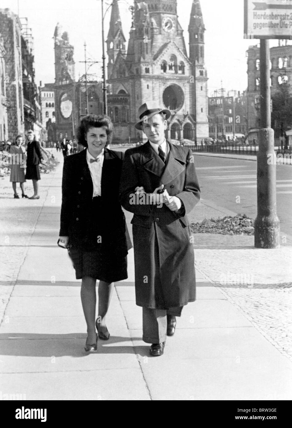 Couple strolling on Tauentzienstrasse, at back the Gedaechtniskirche Church, destroyed to a large extent by Allied bombs in Stock Photo