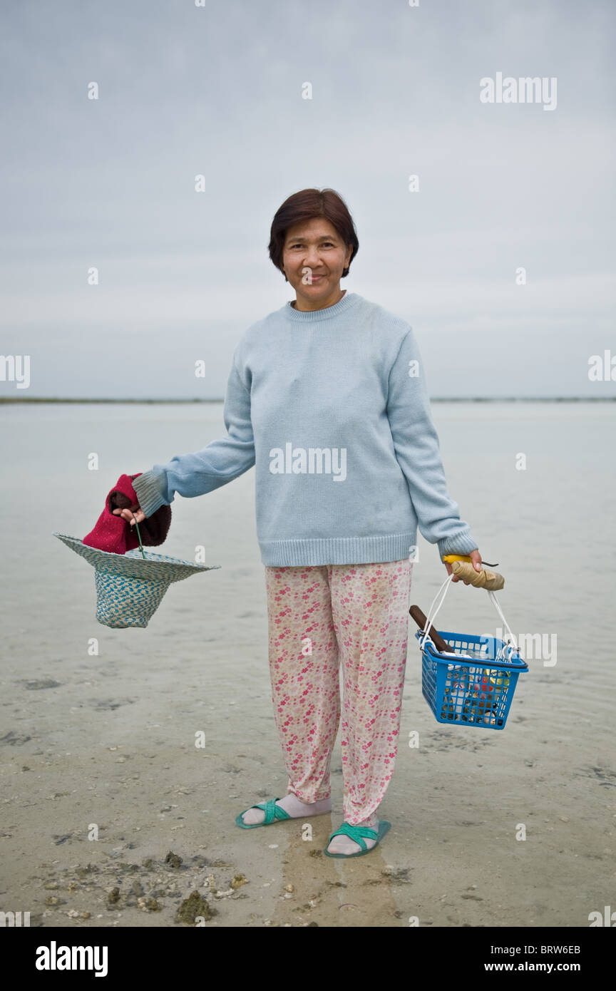 A woman who has been digging for small clams poses for the camera on