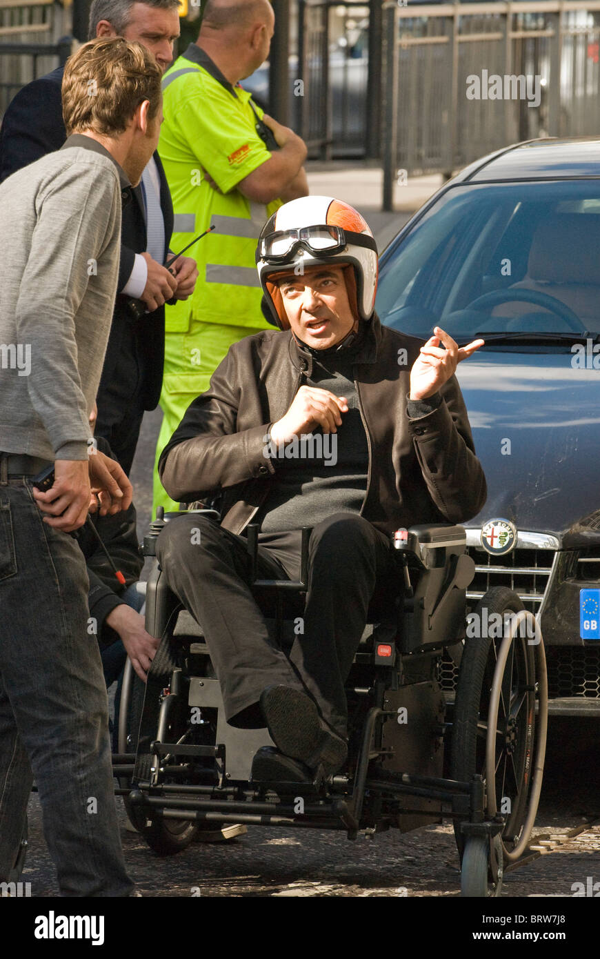 Rowan Atkinson,wearing crash helmet prepares for action on a lawnmower powered wheelchair  set  Johnny English Reborn  London UK Stock Photo
