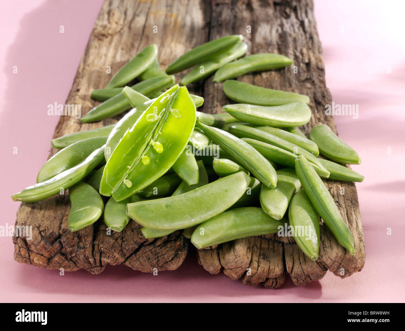 Snap peas (Pisum sativum) on a wooden board Stock Photo