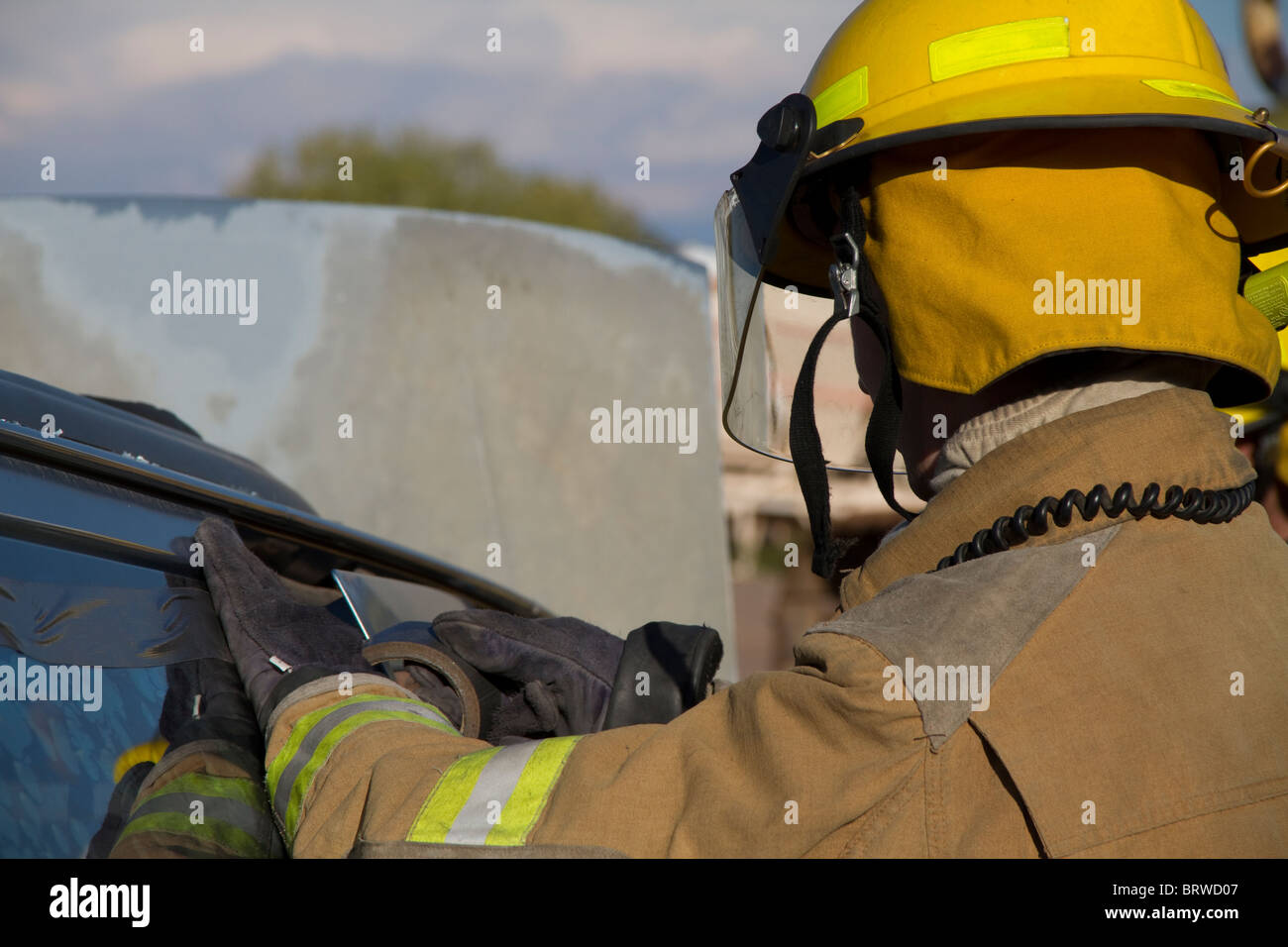 Recruit Firefighter removing a vehicle window during an extrication drill. Stock Photo