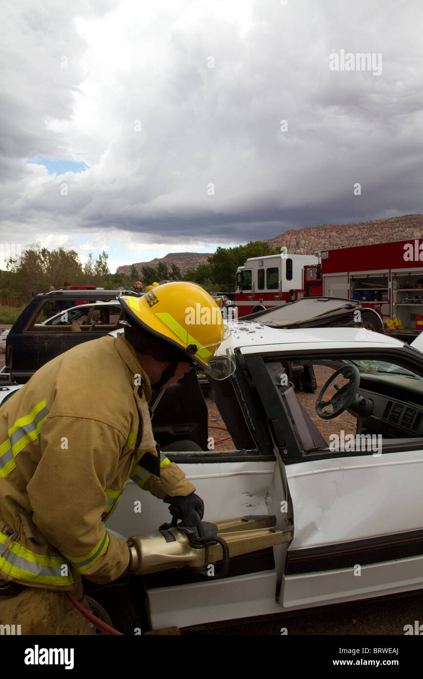 Recruit Firefighter removing a car door during an extrication drill Stock Photo