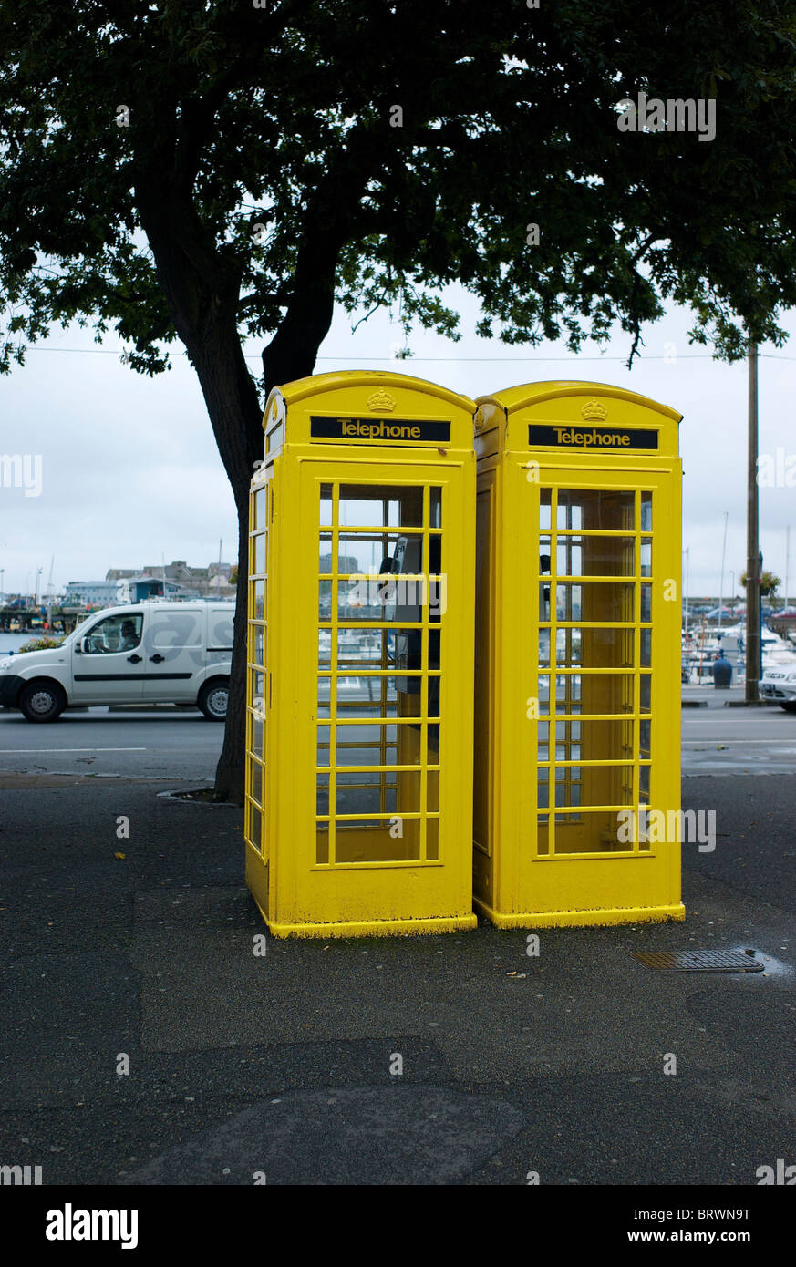 A pair of bright yellow telephone boxes in St Peters Port on the Island of Guernsey in the the Channel Islands. Stock Photo