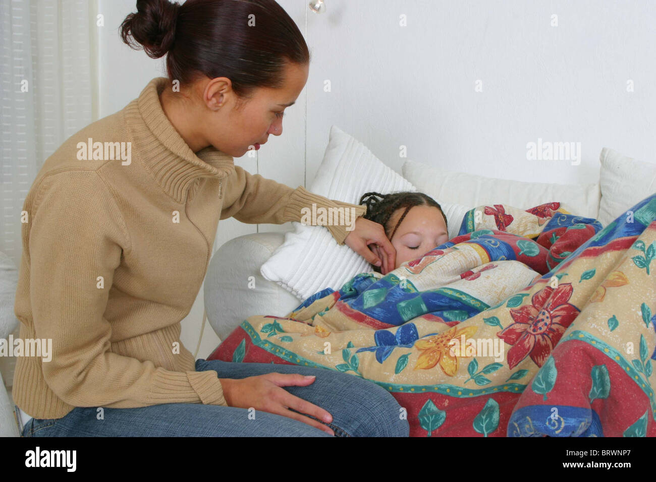 Mother checking her sick daughter asleep with fever in bed Stock Photo