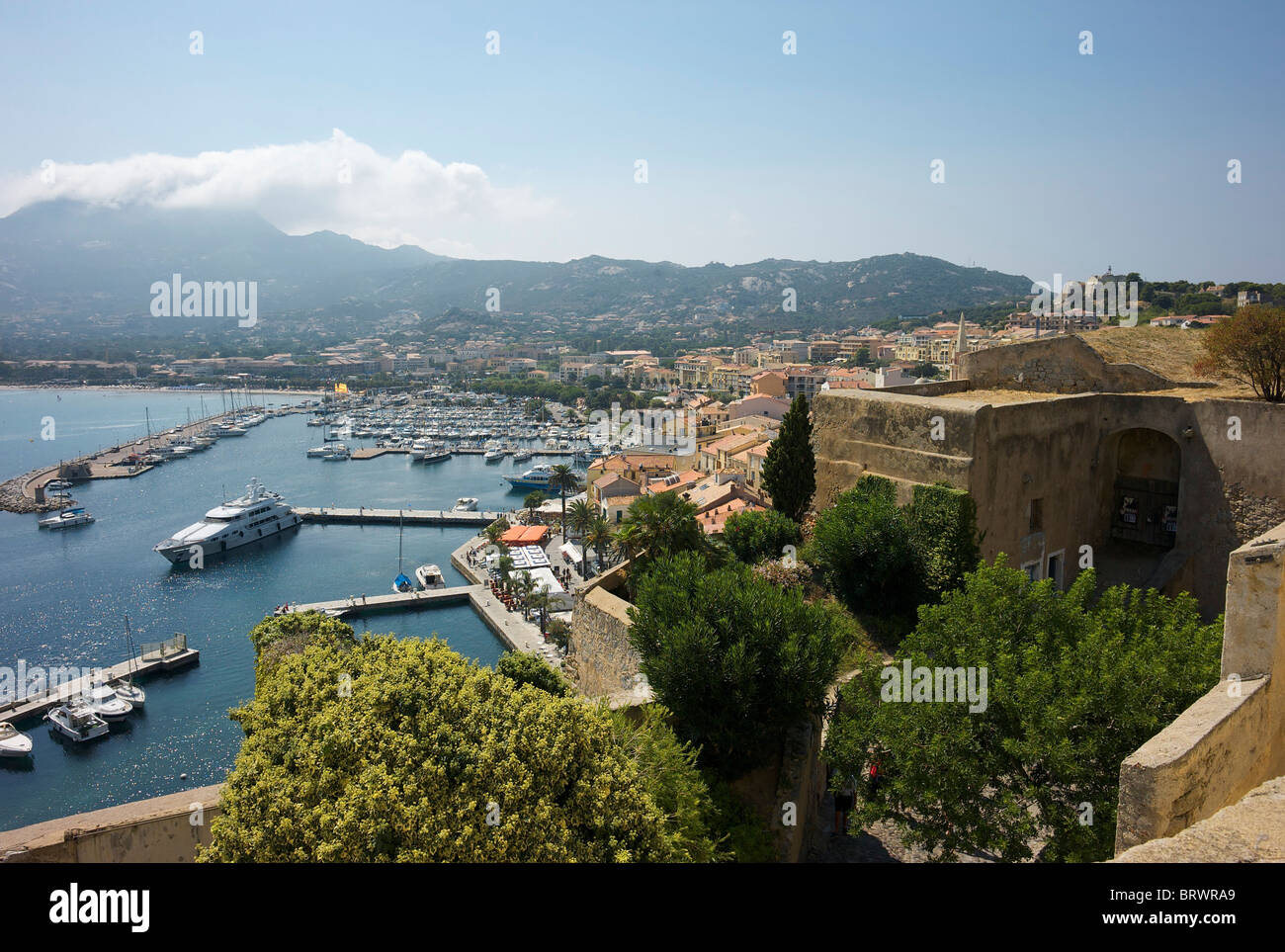 View of Calvi harbour from the Citadel with the mountains in the distance. Stock Photo