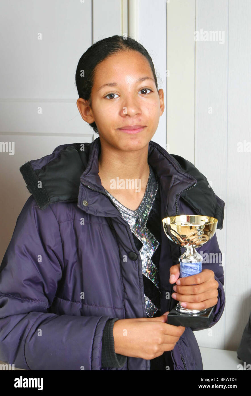 Casual Latin American teenage girl with serious expression holding goblet price in hands Stock Photo