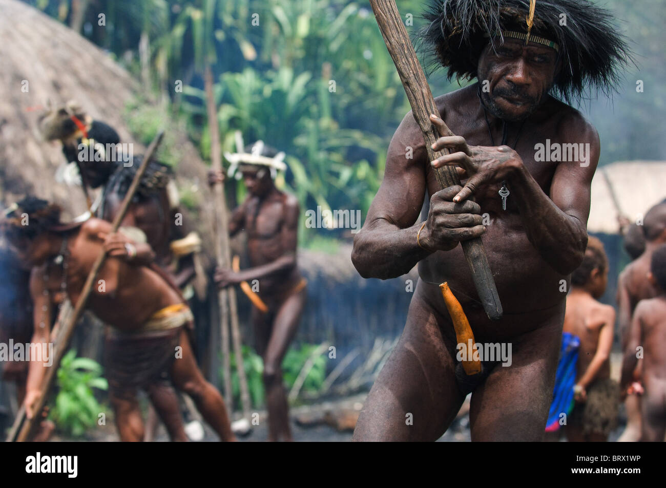 - Go away! The Papuan banishes from the village, swinging a stick. Indonesia. Papua New Guinea. Village of people Dani Dugum. Stock Photo