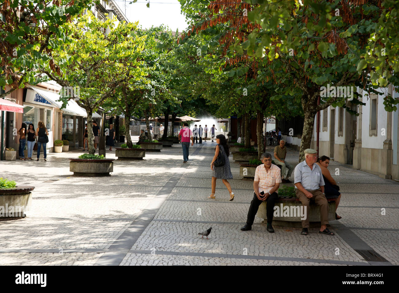 Quiet summer street scene in Braga Portugal. People resting in the shade and walking around the pleasant cobbled streets. Stock Photo