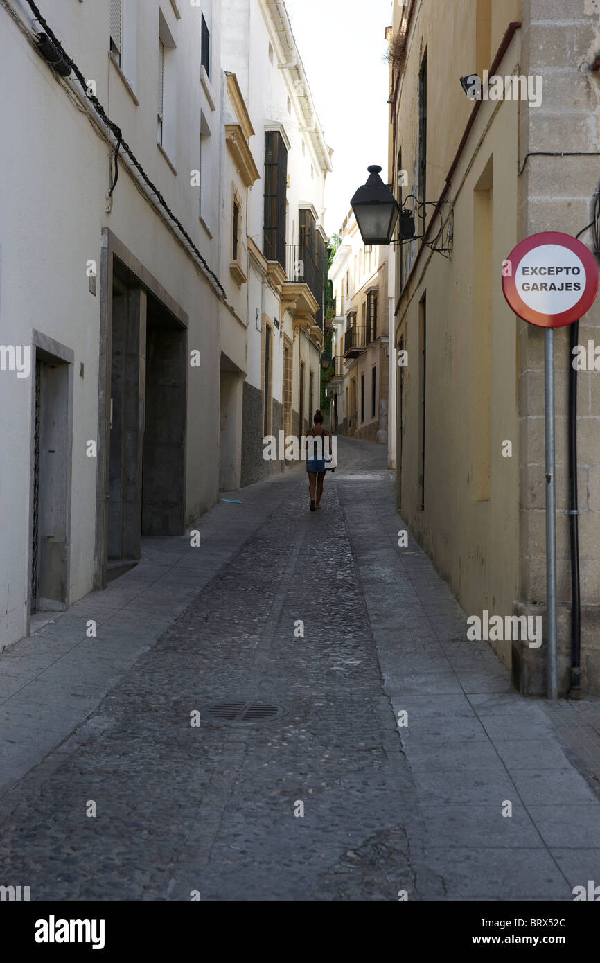 Woman walking alone up narrow street in Jerez Spain. No traffic to be seen. Stock Photo