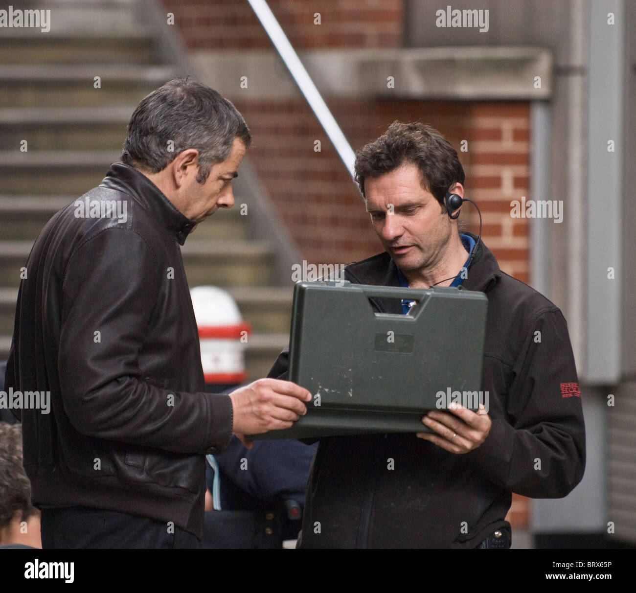 Rowan Atkinson discussion with a technician on set of Johnny English Reborn 2, in Pilgrim Street, EC4, City of London. Stock Photo