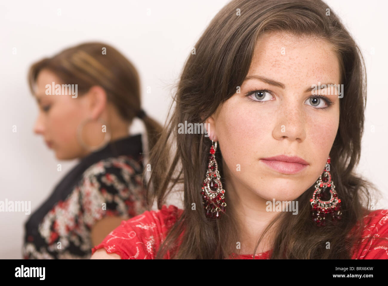 Two teenage female friends having a dispute or argument, turning back to each other, disregarding, one female look at camera Stock Photo