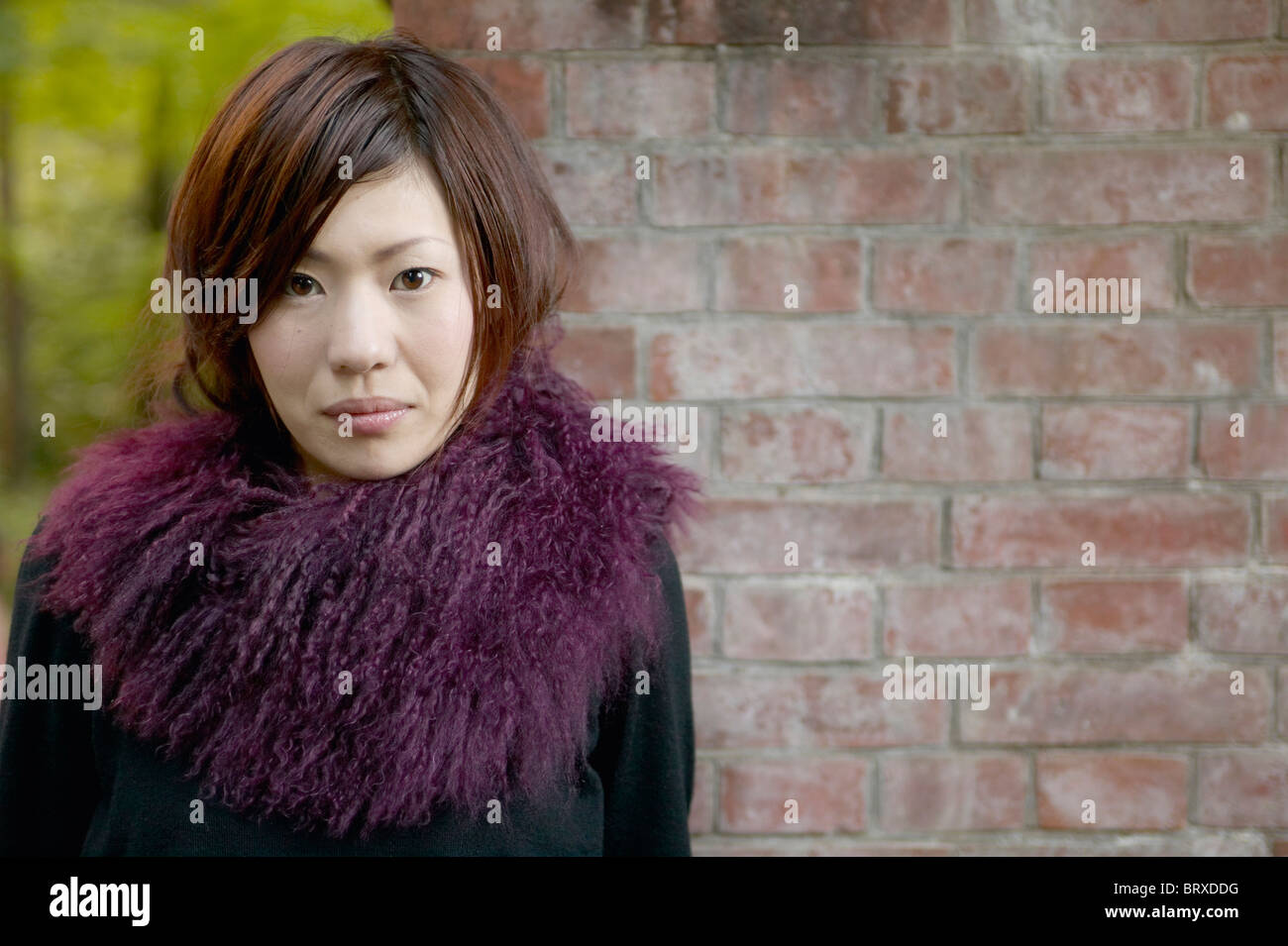 Portrait of Young Woman Against Brick Wall Stock Photo - Alamy