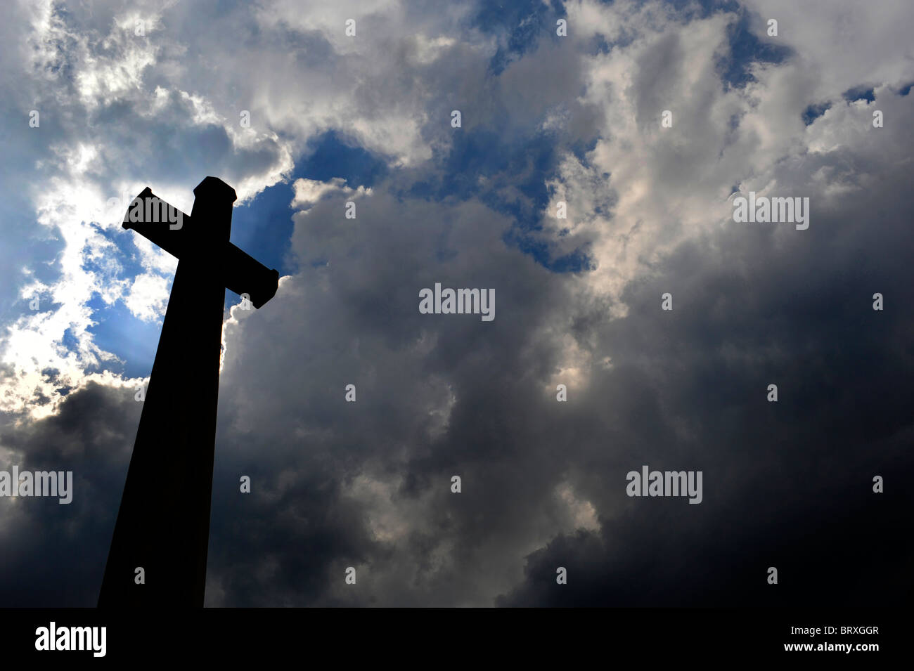 A cross from one of the many Commonwealth War  memorials in Flanders, seen against a thunderous sky. Stock Photo
