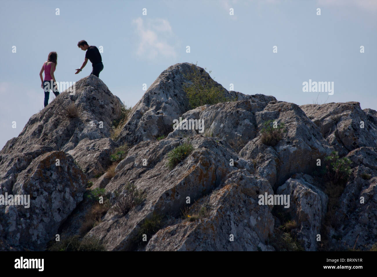 A young couple climbs on the Acrocorinth fortress in Ancient Corinth Stock Photo