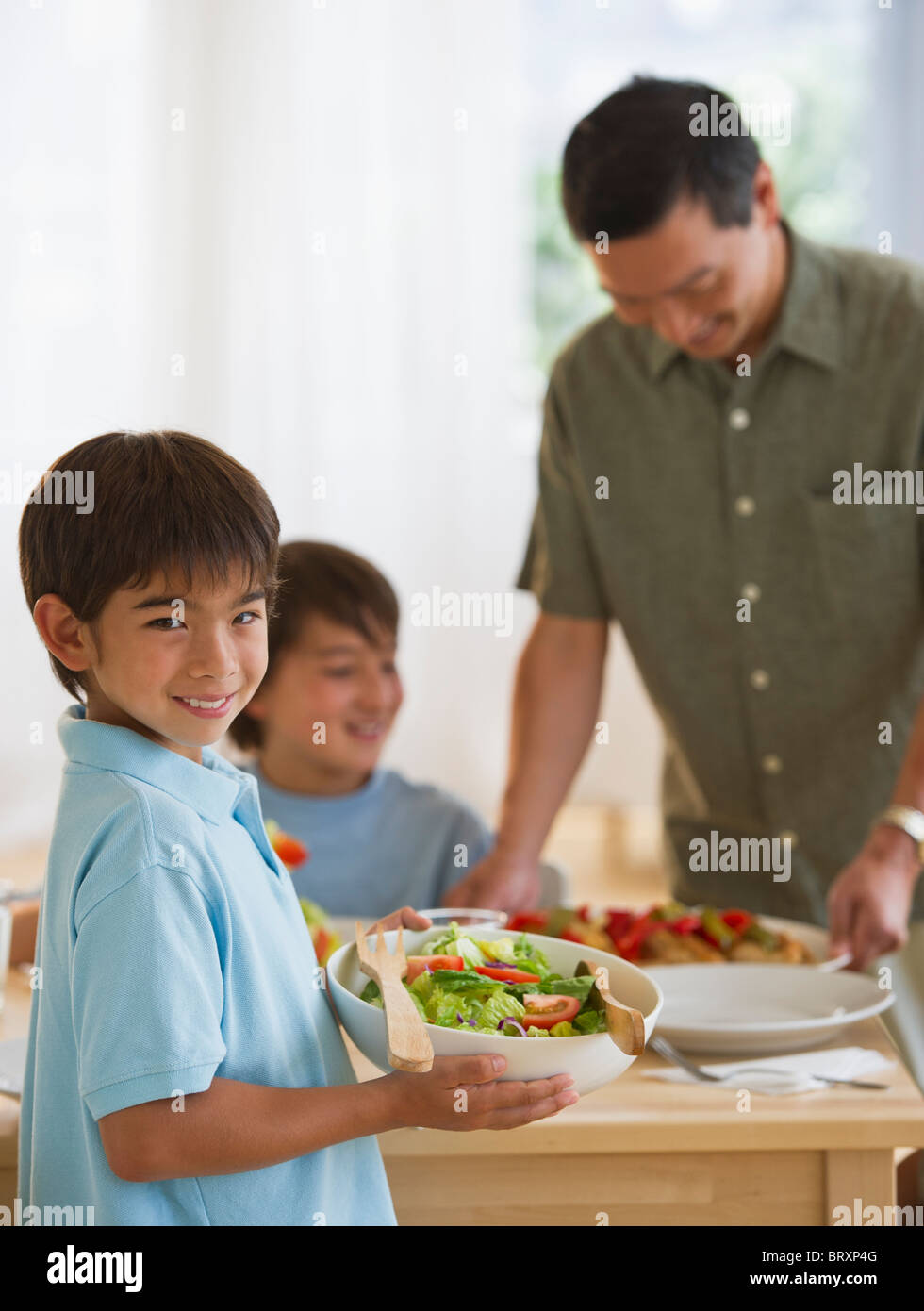 Smiling boy serving salad to family Stock Photo Alamy