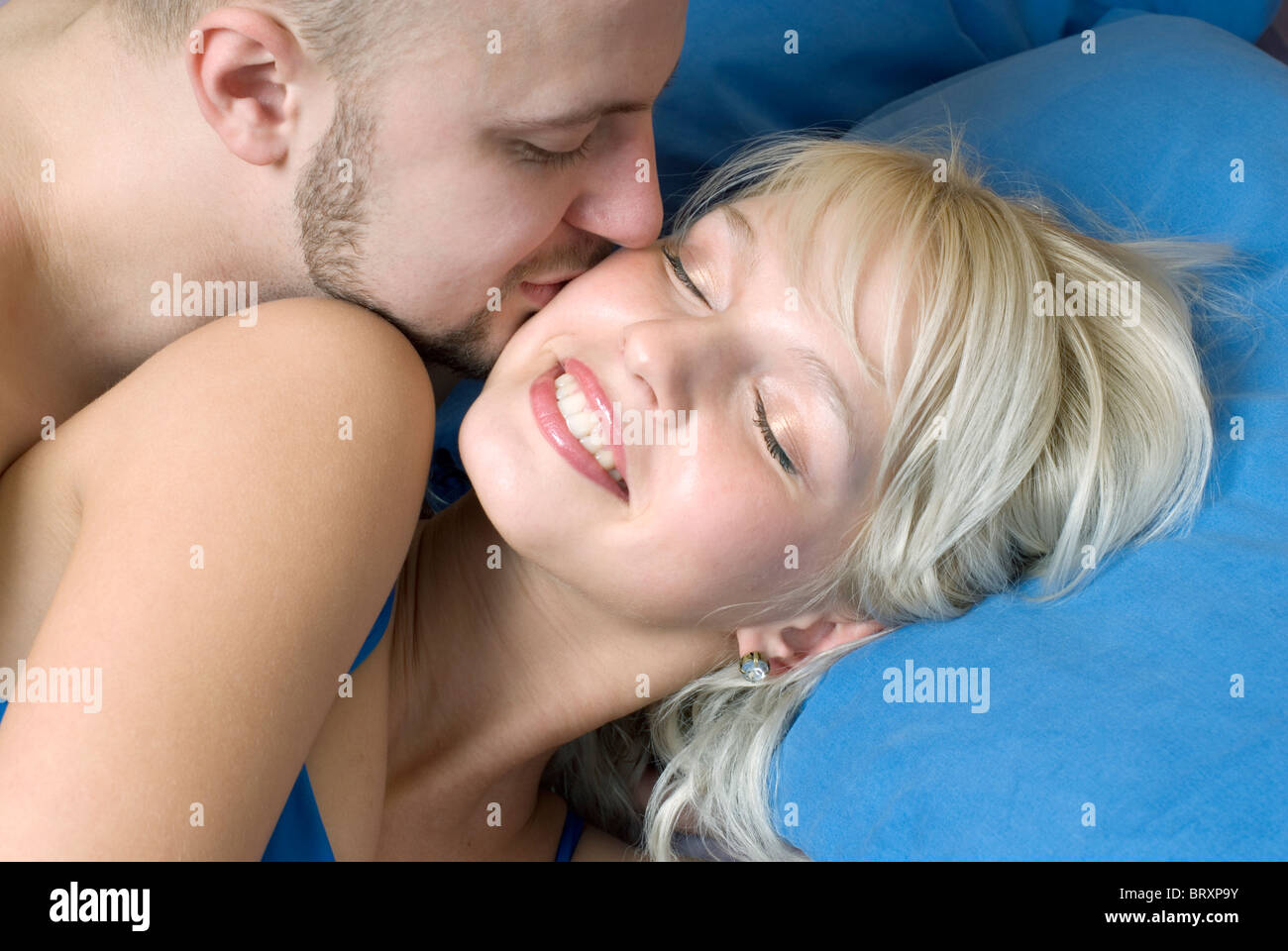 Close-up of young man kissing woman in bed Stock Photo