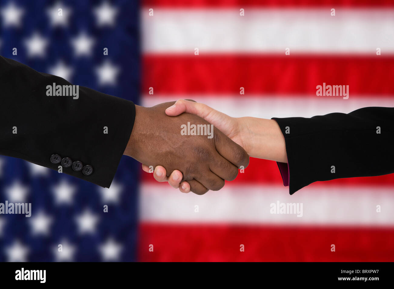 Close-up of people shaking hands against American flag Stock Photo