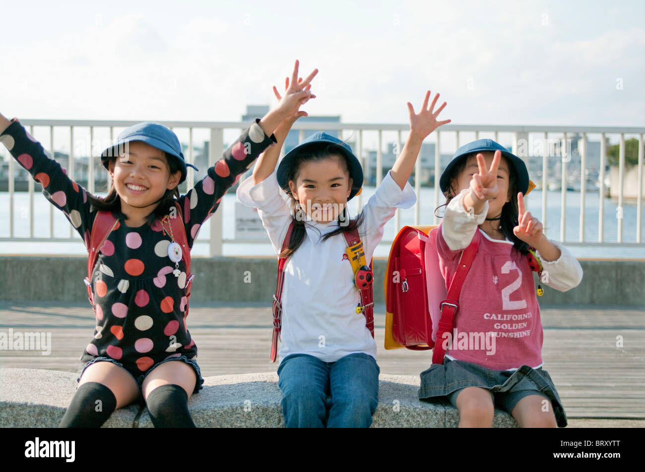 Girls with arms raised and peace sign Japan Stock Photo