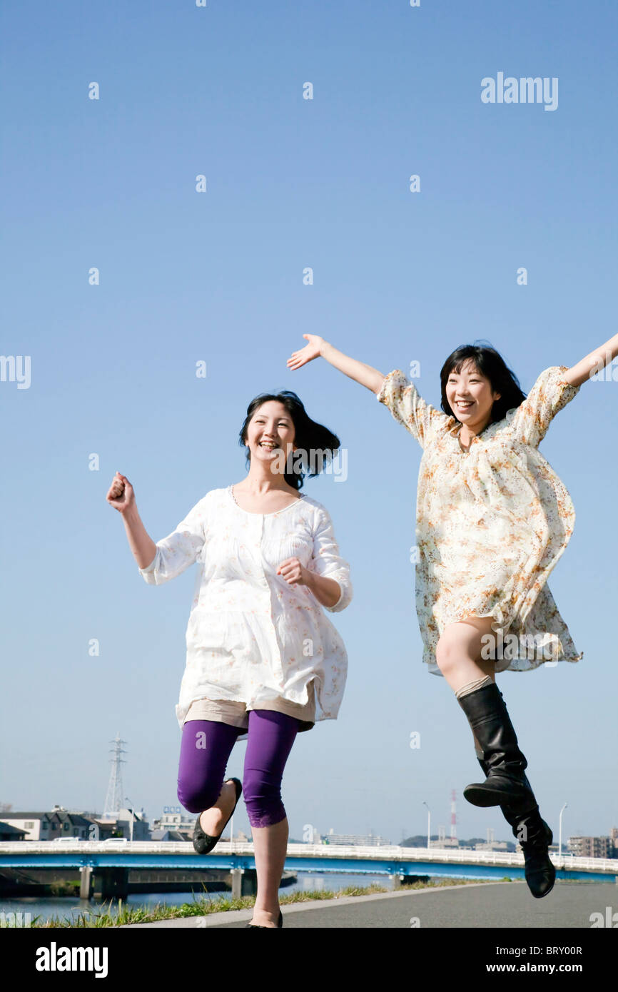 Tow Young Women Jumping Under Blue Sky Stock Photo - Alamy