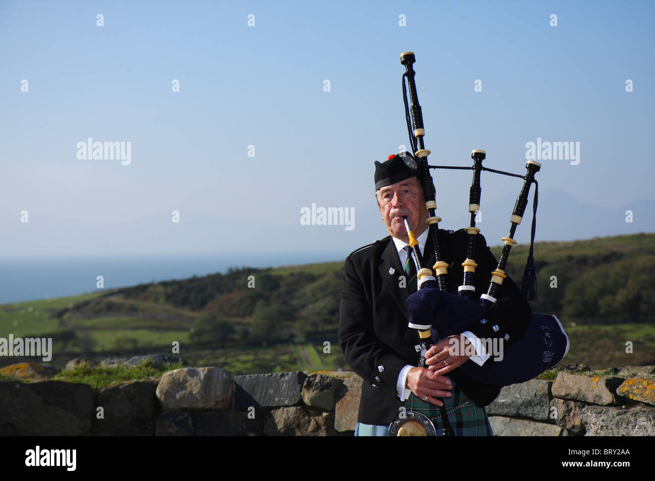 Shot of a traditional Scottish Bagpipe Player playing the bagpipes outside at a wedding on the West Coast of Scotland Stock Photo