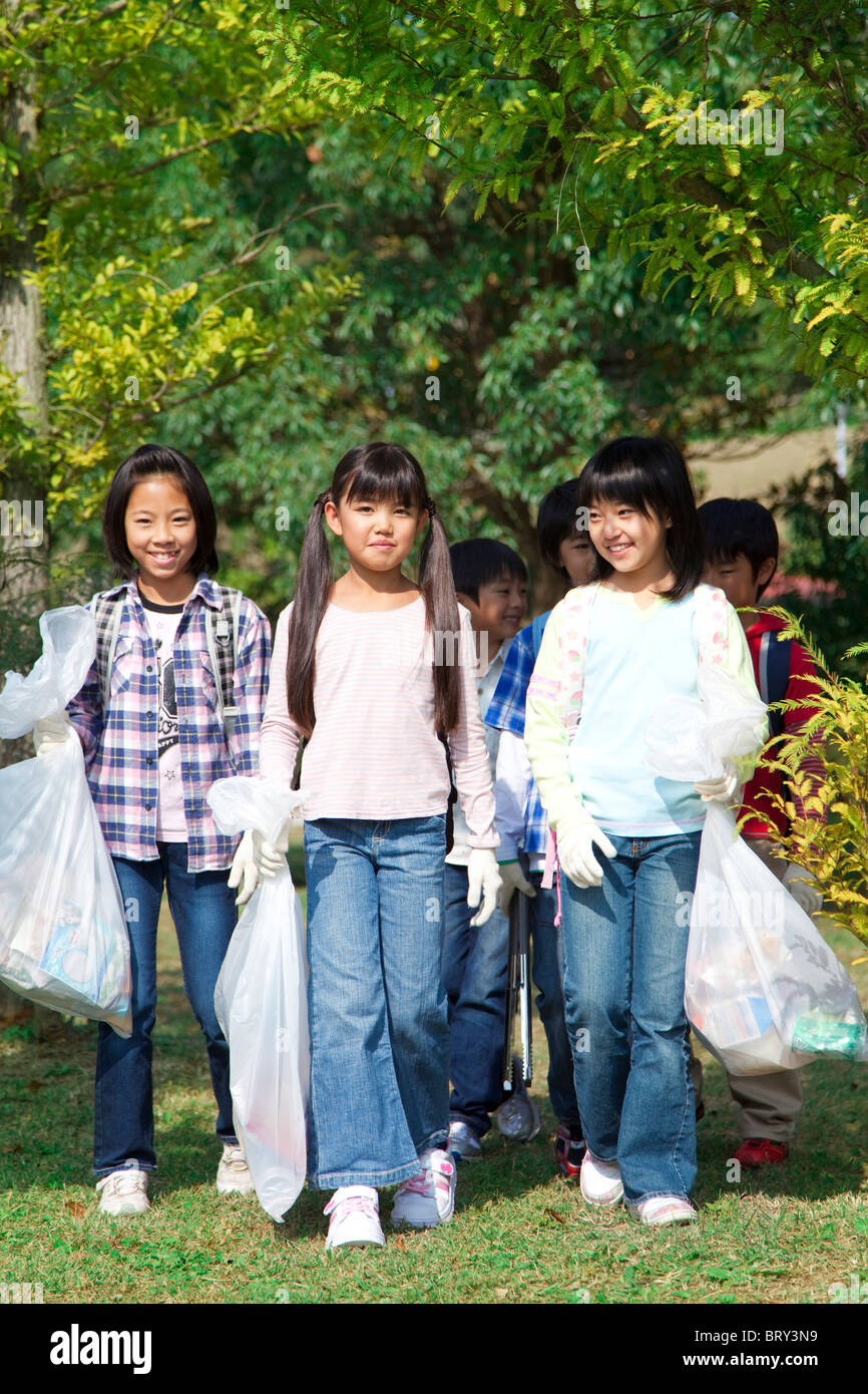 Schoolgirls holding bags for recycling, smiling Stock Photo