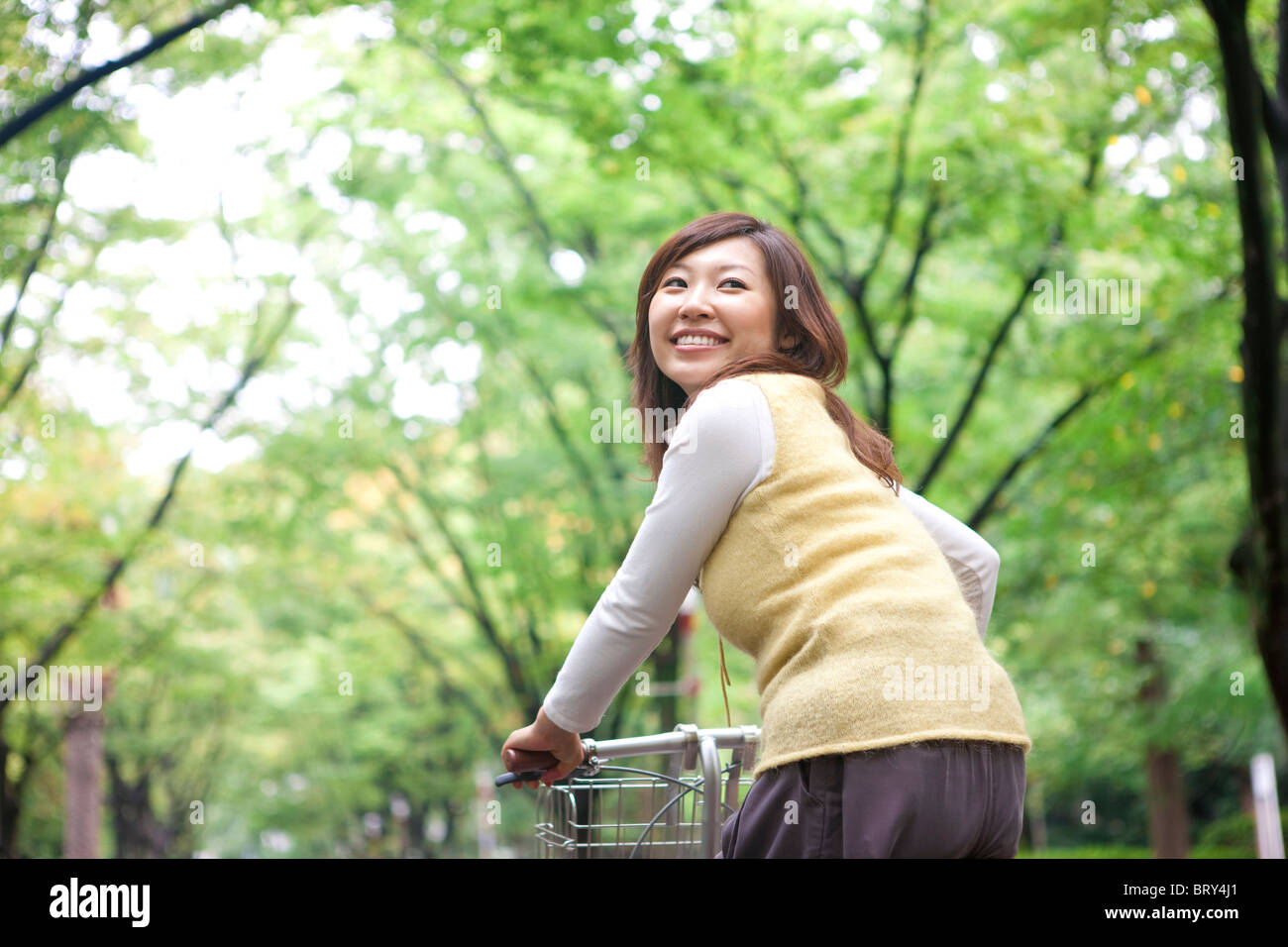 Young woman riding bicycle, smiling Stock Photo