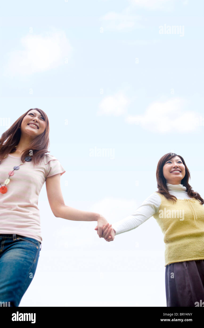 Two young women walking hand in hand, smiling, copy space Stock Photo ...